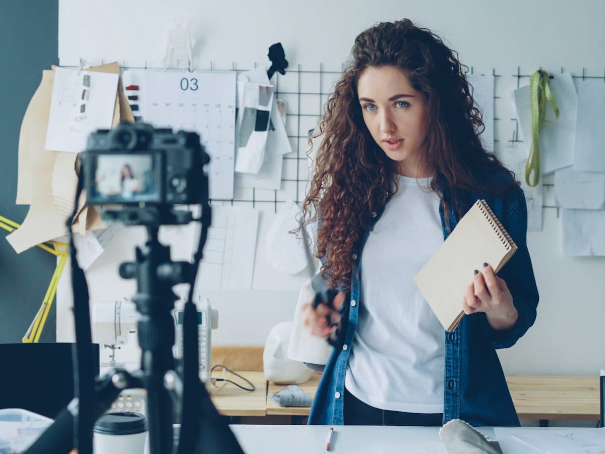 Content creator recording a branded tutorial in a studio with camera gear and creative notes nearby.